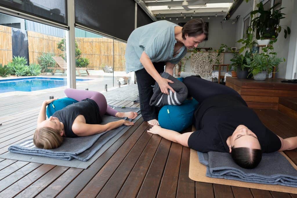Showing group yoga class using props for calm, guided relaxation
