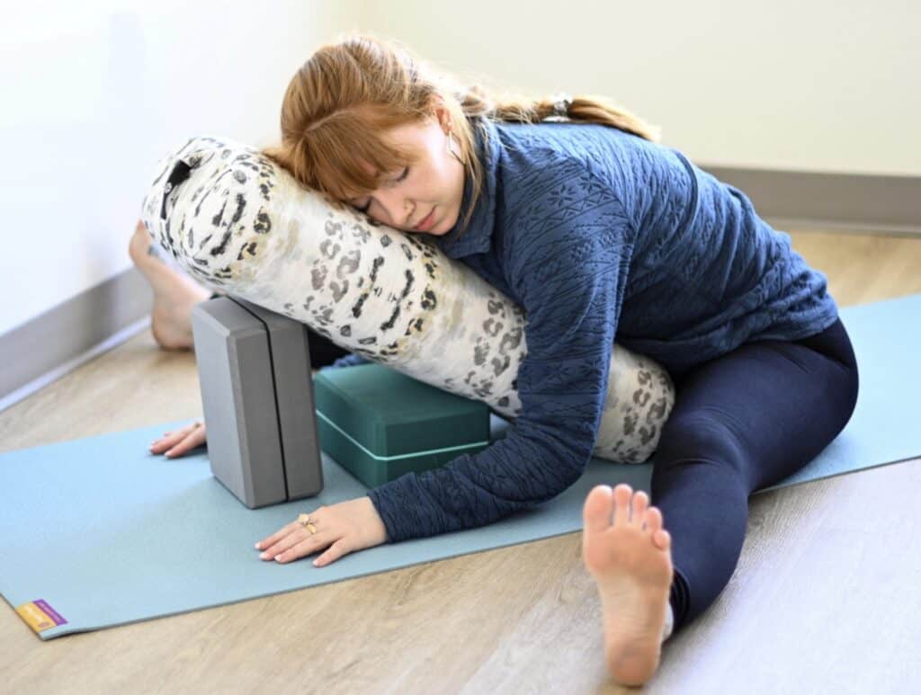 Showing a woman in a restorative yoga pose using props for cancer support therapy