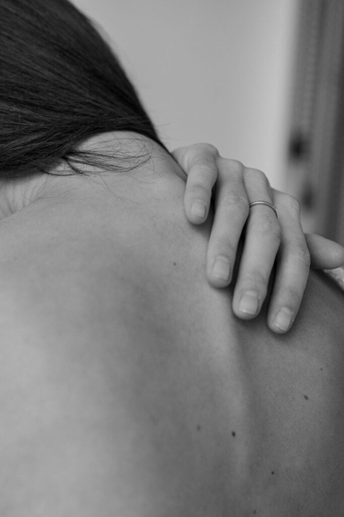 Monochrome close-up of a hand on a woman's shoulder, evoking introspection.