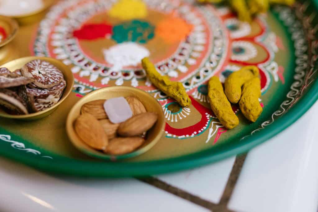 Close-up of a vibrant Indian festival tray with almonds, turmeric, and colors.